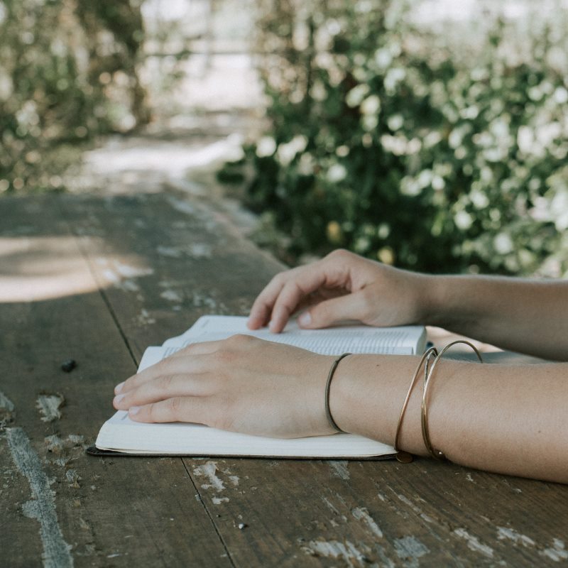 Hands resting on a book placed on a table